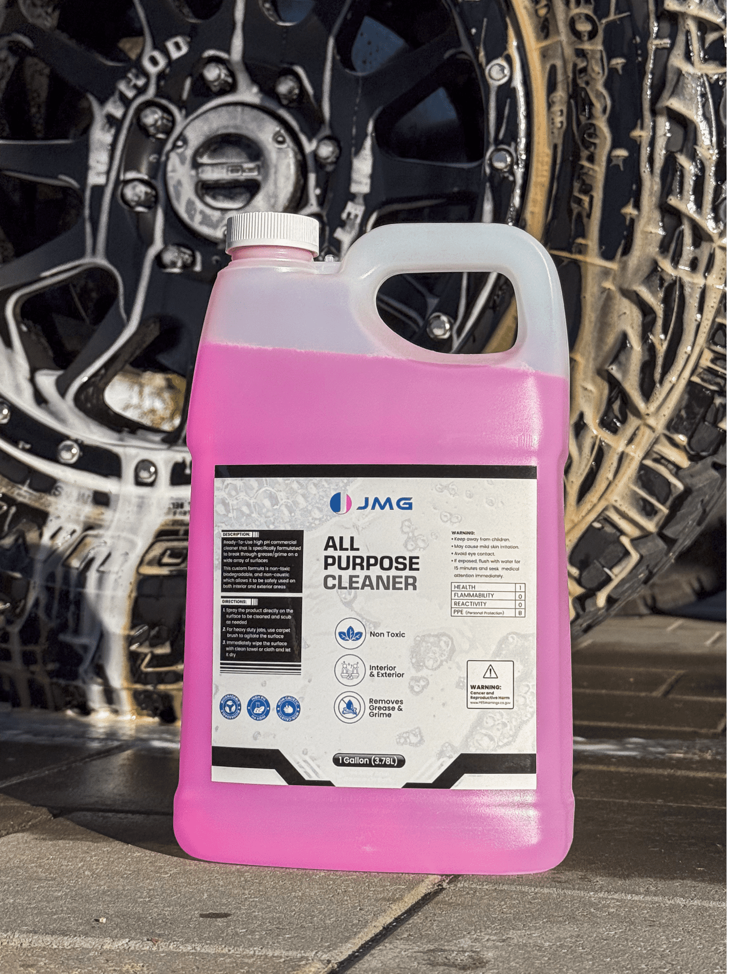 JMG All Purpose Cleaner gallon in front of truck tire and rim covered in foam from IK Foam Sprayer during detailing at San Francisco auto shop